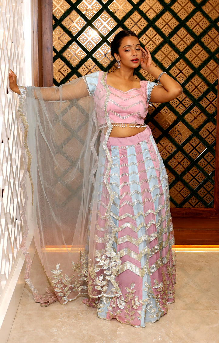 Woman in a pink and blue traditional outfit with a decorative background
